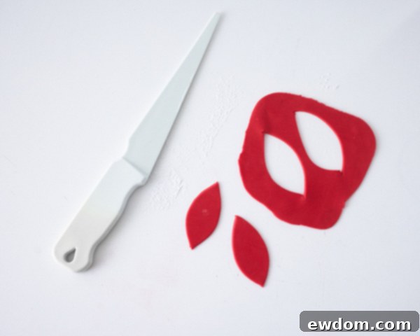 Matryoshka Magic Cake 13 Crafting the red fondant bow for the Russian nesting doll cake: cutting leaf shapes and attaching them. Cake by Cakegirls.