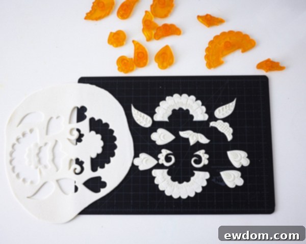 Matryoshka Magic Cake 16 Cutting intricate floral applique pieces from white fondant using a folk art cutter set for the Russian nesting doll cake. Cake by Cakegirls.