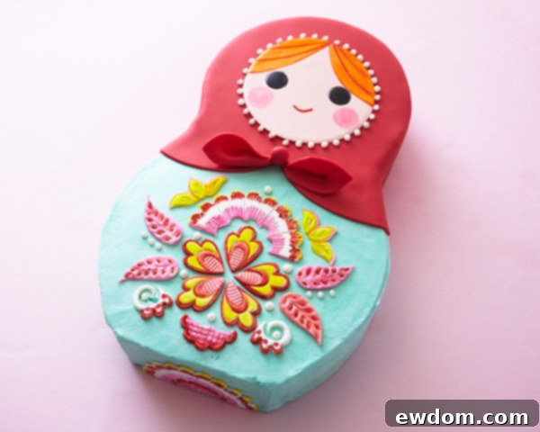 Matryoshka Magic Cake 5 Overview of the Russian nesting doll cake with its unique shape and vibrant red headscarf. Cake by Cakegirls.