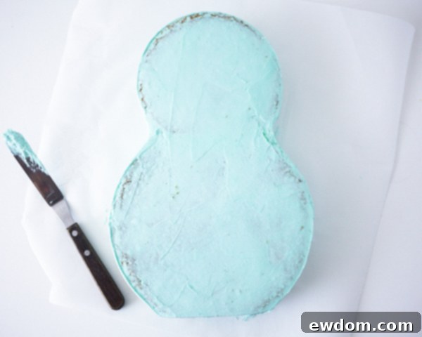 Matryoshka Magic Cake 9 Applying aqua buttercream to the cake for the Russian nesting doll base, demonstrating the crumb coat and final smoothing. Cake by Cakegirls.