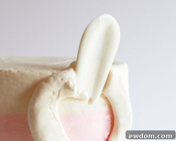 The first white chocolate petal is carefully placed onto the buttercream circle on the cake, rounded side facing out.