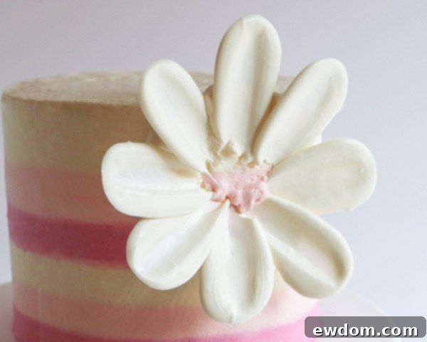 The first complete row of white chocolate petals forming the outer edge of the flower is shown on the buttercream base.