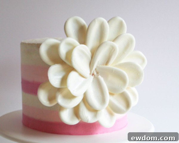 The nearly complete white chocolate flower on the cake, with all rows of petals in place, awaiting its final center.