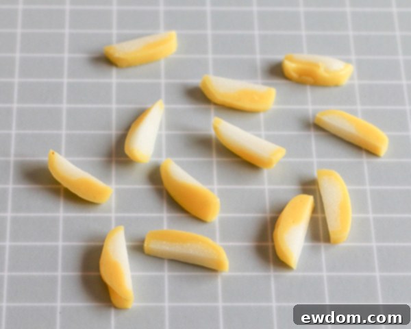 A collection of finely cut yellow taffy pieces, ready to be bundled and placed into the center of the chocolate flower.