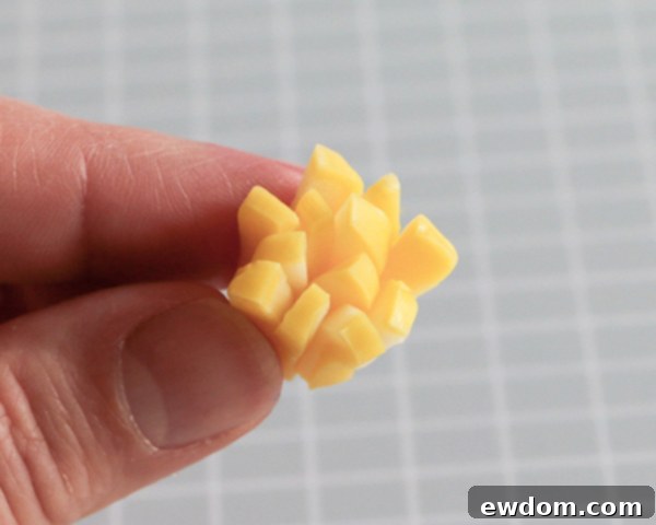 The cut yellow taffy slices are gathered into a small bundle, pinched at one end to form a pointed base for the flower center.