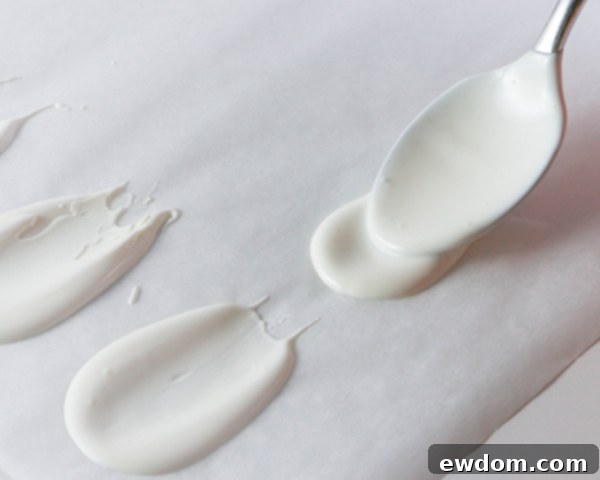 The melted chocolate puddle is carefully smeared with the back of a spoon to shape it into a delicate petal on parchment paper.