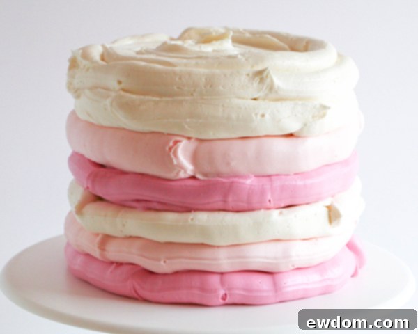 Piping horizontal stripes of pink and white buttercream onto a cake