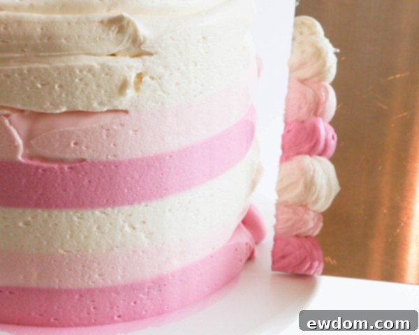 Using a bench scraper to smooth striped buttercream on a cake