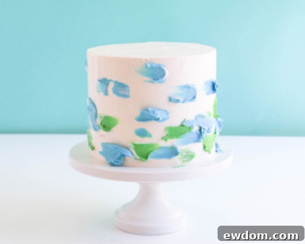 Pink Paradise Flamingo Cake 33 Applying dots of green and blue buttercream to the white frosted cake for the watercolor effect