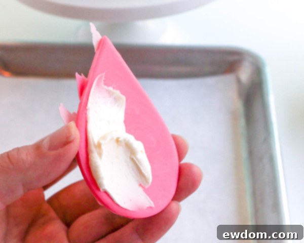 Pink Paradise Flamingo Cake 37 Applying buttercream to the back of the feathered flamingo body for attachment to the cake