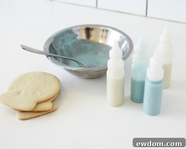 Glaze preparation for Snow Globe Cookies - Blue and white cookie glaze in squeeze bottles, ready for decorating by Cakegirls for TheCakeBlog.com