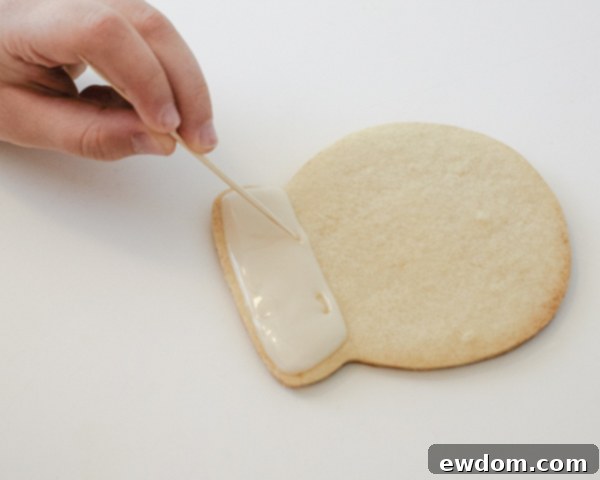 Decorating Snow Globe Cookies - Flooding the base of the snow globe with white cookie glaze by Cakegirls for TheCakeBlog.com