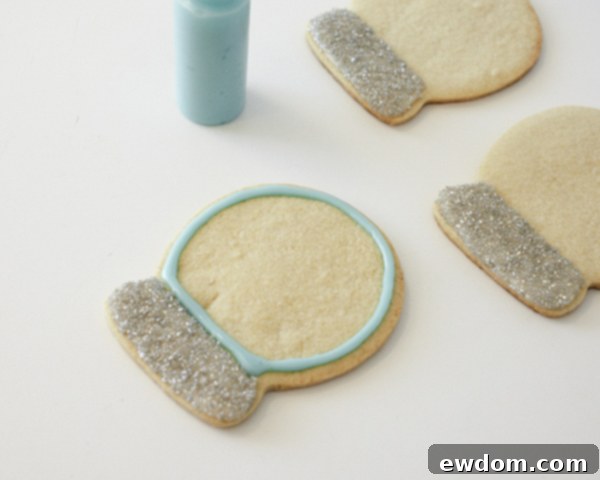 Decorating Snow Globe Cookies - Piping blue cookie glaze for the sky portion of the snow globe by Cakegirls for TheCakeBlog.com