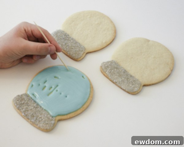 Decorating Snow Globe Cookies - Flooding the sky with blue cookie glaze for the snow globe effect by Cakegirls for TheCakeBlog.com