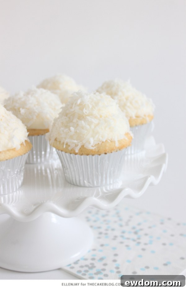 Coconut Cupcakes - fluffy coconut cupcakes made with coconut milk and topped with smooth coconut buttercream and coconut flakes | by ellenJAY for TheCakeBlog.com