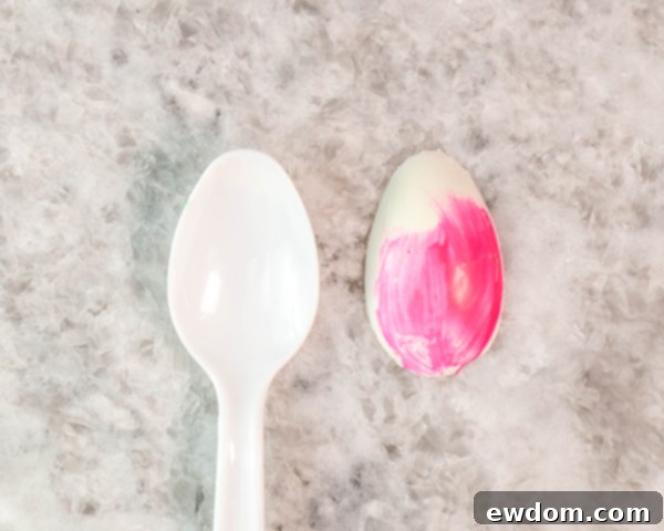 Gently un-mold chocolate petals from spoons, stems from straws, and leaves from parchment paper, preparing for assembly.
