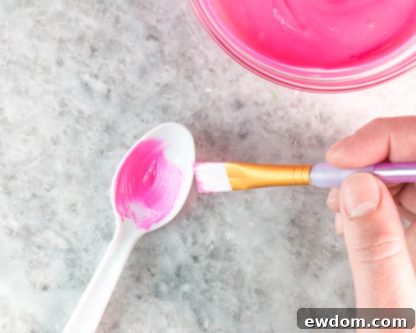 Paint strokes of bright pink coating chocolate into plastic spoons, concentrating color at the base for natural tulip petal shading.