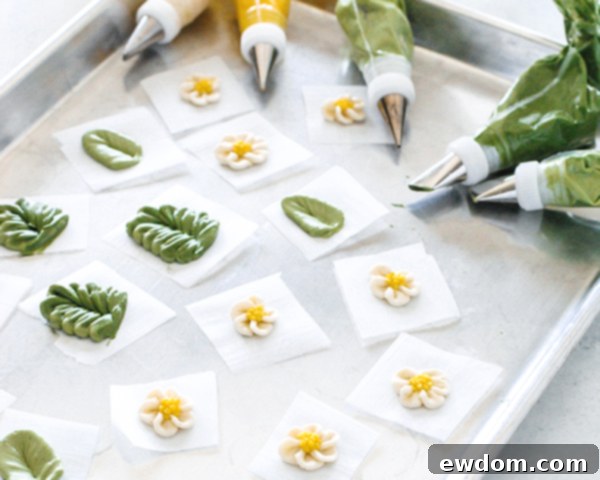 Spring Blossom Wreath Cake 8 A selection of beautifully piped buttercream leaves and cherry blossoms on parchment paper, ready to be chilled and placed on the cake.
