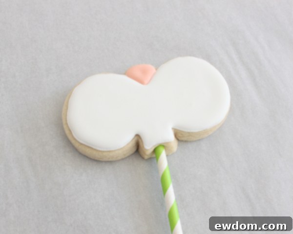 A tray of semi-decorated bunny cookie pops, drying after the initial flood icing