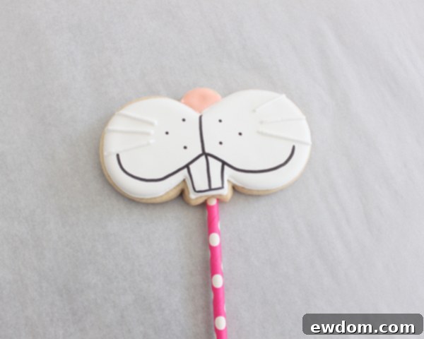 Drawing bunny eyes and mouth onto a dry cookie with a black edible marker