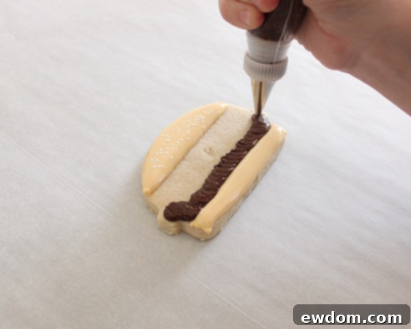 Adding orange royal icing cheese on top of the hamburger patty