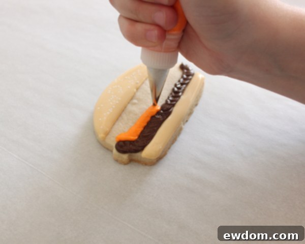 Piping lime green royal icing lettuce for hamburger cookies