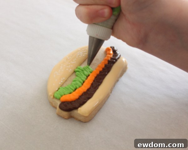 Adding red royal icing tomato slices to hamburger cookies