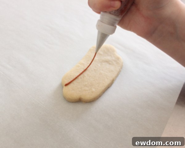 Piping ivory royal icing outline for hot dog bun