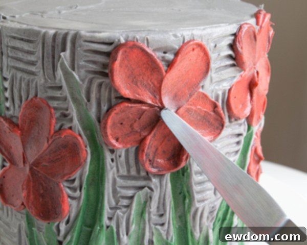 Adding a black buttercream center to a painted flower using a tapered spatula