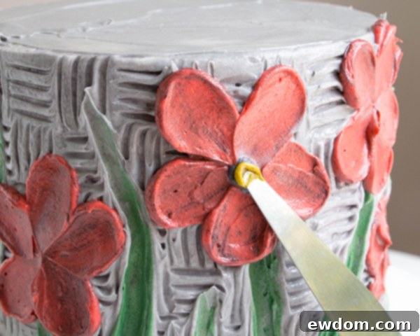 Adding a final yellow highlight to the black buttercream flower centers with a tapered spatula