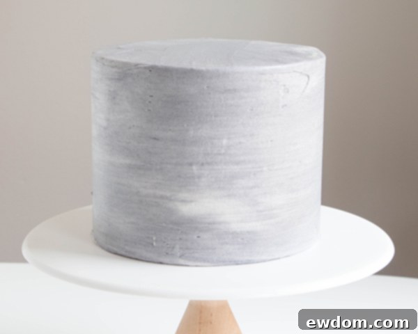 Applying streaky black buttercream to a cake for the base layer, creating a textured canvas