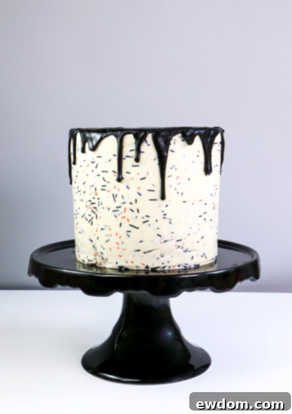 The top of the cake covered in a smooth, dark chocolate ganache, with elegant drips cascading down the sides, a crucial element of the carousel cake | by Erin Gardner for TheCakeBlog.com