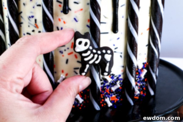 Adhering a chocolate animal skeleton to a candy stick with melted chocolate, bringing the carousel to life with its spooky riders | by Erin Gardner for TheCakeBlog.com