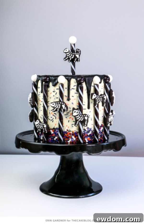 Close-up of a chocolate-dipped animal cracker skeleton with white chocolate details, ready to adorn the Halloween cake carousel | by Erin Gardner for TheCakeBlog.com