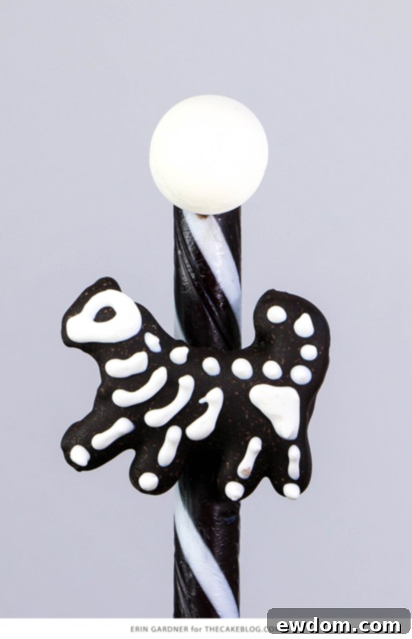 The completed Animal Skeleton Carousel Cake, featuring black and white candy sticks, licorice drops, and an array of chocolate animal skeletons for a festive Halloween or Dia de los Muertos treat | by Erin Gardner for TheCakeBlog.com