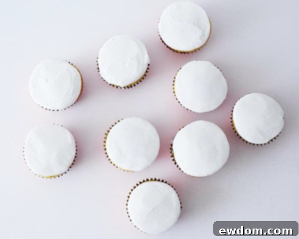 First step in decorating Christmas Present Cupcakes: cupcakes baked in red foil liners and smoothly iced with white frosting.