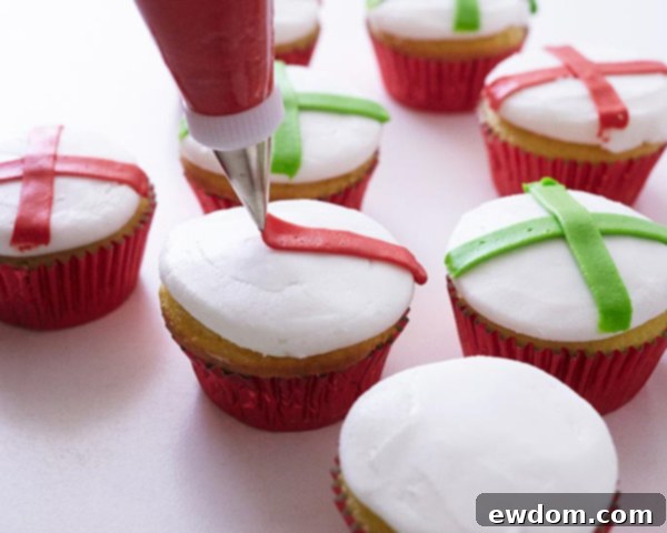 Detail view of a green criss-cross ribbon being piped onto a Christmas Present Cupcake, demonstrating the technique for uniform lines.