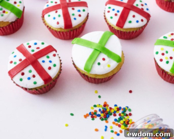Christmas Present Cupcake decorated with a red ribbon and colorful confetti quin sprinkles, creating a playful polka dot pattern.