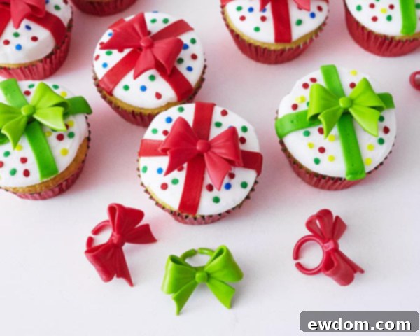 Final step for Christmas Present Cupcakes: a green novelty bow ring placed on top of a decorated cupcake, completing the gift box look.