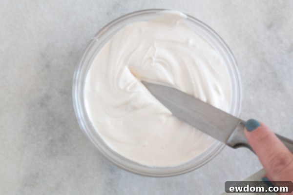 Dipping the larger knife into melted white chocolate to coat one side evenly.