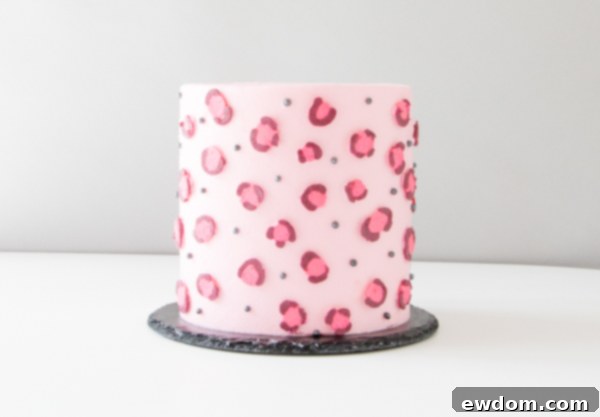 Chic Leopard Buttercream 14 Gently peeling off waxed paper backing from a buttercream leopard spot on a cake