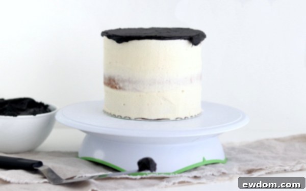 Sorceress's Potion Cake 11 Applying black buttercream to the top of the crumb-coated cake on a turntable