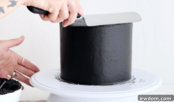 Sorceress's Potion Cake 13 Creating sharp edges on the black buttercream cake with an angled spatula