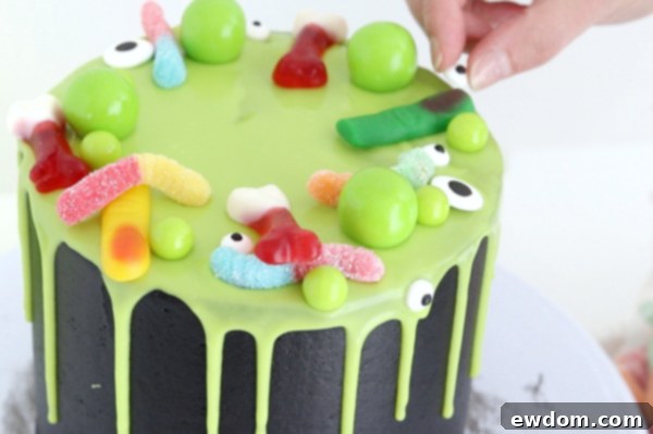 Sorceress's Potion Cake 17 Adding various Halloween candies like gummy worms and eyeballs to the cauldron cake