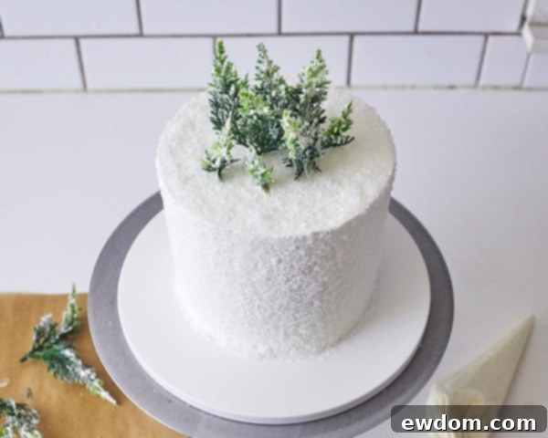 Enchanted Snowflake Cake 15 Arranging buttercream-frosted novelty pine trees on top of the cake