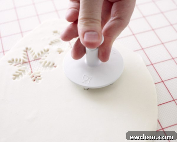 Enchanted Snowflake Cake 7 Fondant rolled out on a surface with snowflake cutters nearby