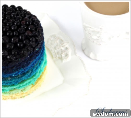 Stack of freshly baked blue cake layers with lemon curd being spread