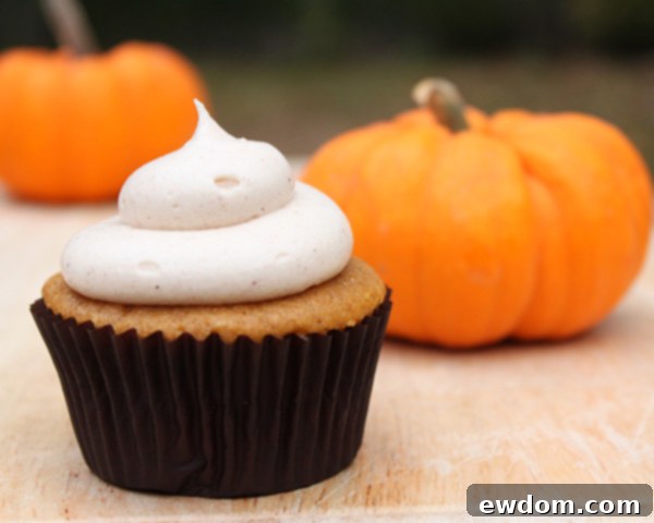 Spiced Pumpkin Delights 3 Closeup of a freshly baked pumpkin cupcake with a generous swirl of frosting